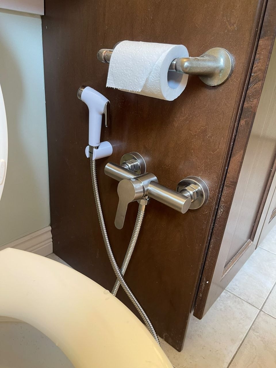 Installed handheld bidet sprayer beside a toilet